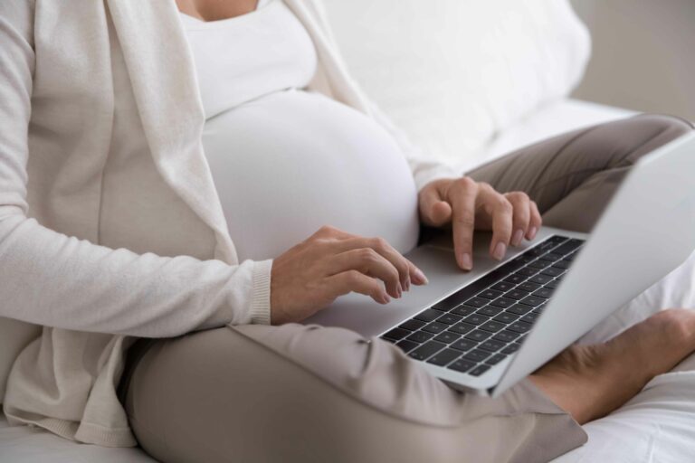 Heavily pregnant woman booking an online counselling sessions using her laptop
