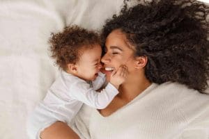 A mother laughing and relaxing with her baby.