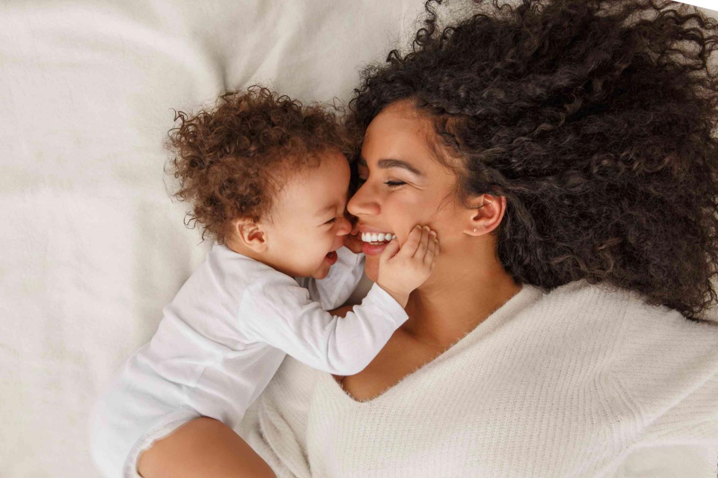 A mother laughing and relaxing with her baby.