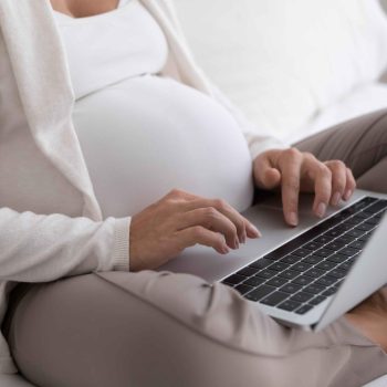 Heavily pregnant woman booking an online counselling sessions using her laptop.